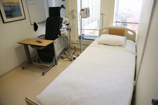 Image of hospital room with bed, chair, and desk.