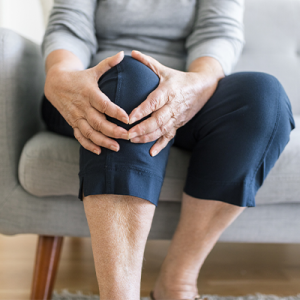 Elderly woman's hands resting over her bent knee