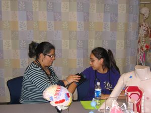 Instructor showing young student how to take a blood pressure