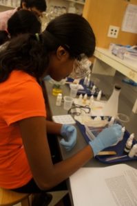 Young girl in safety goggles working at a lab bench