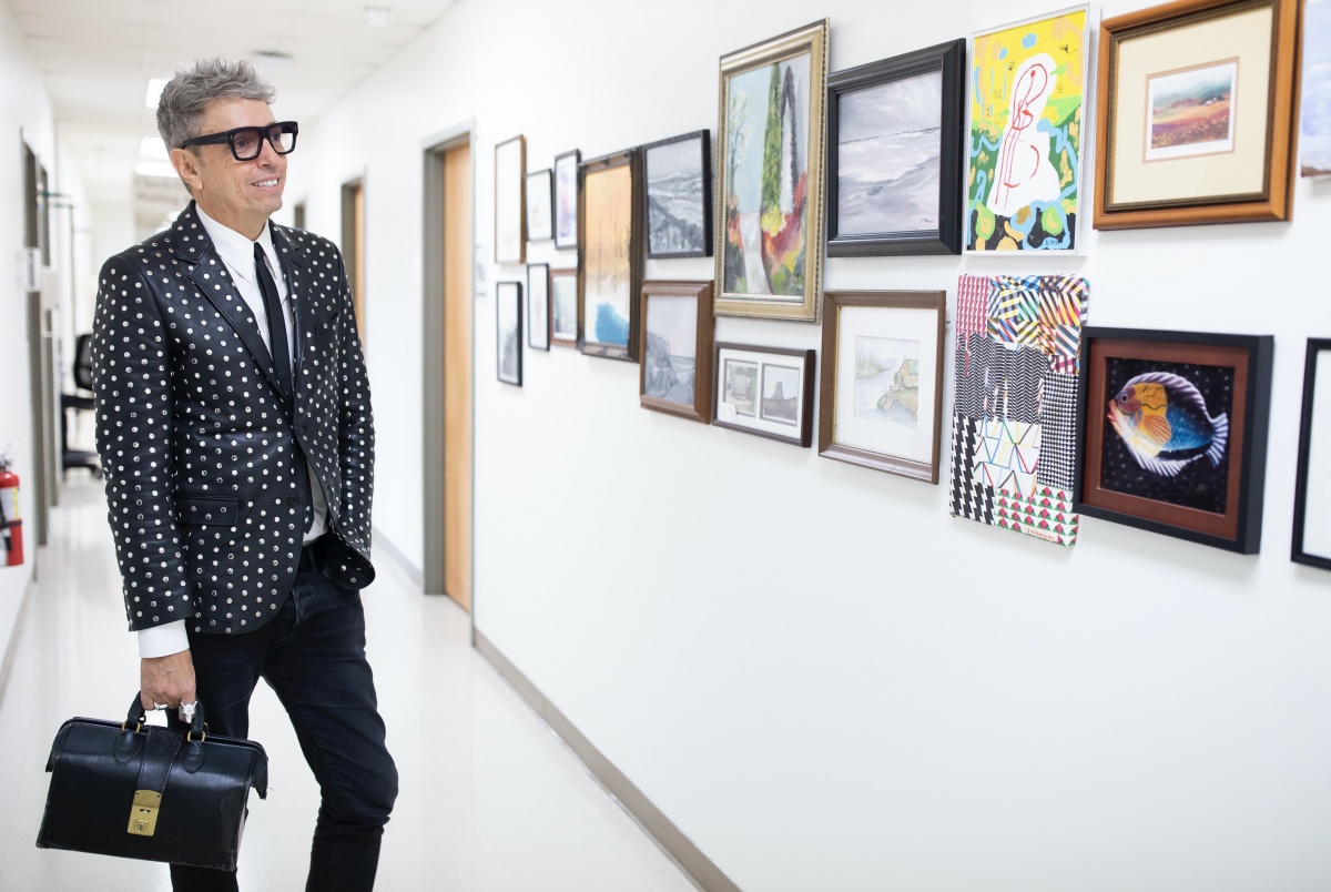 Rick Bedlack walks down hallway in clinic looking at art on the walls