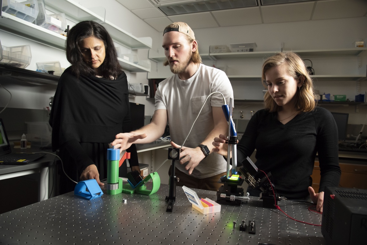 three people use a scope in a lab