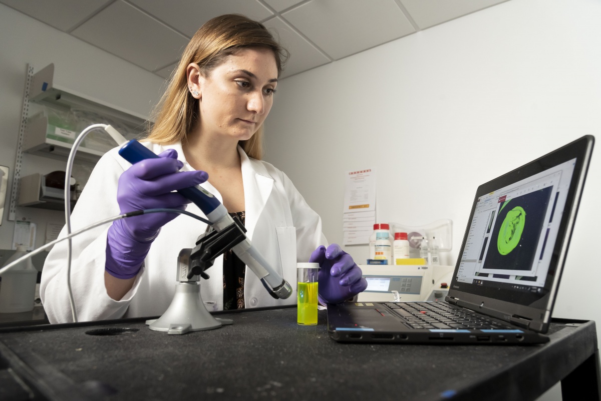 woman in lab using optical technology device and laptop