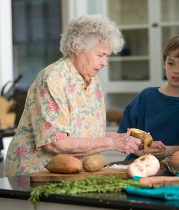 elderly woman peeling potatos in her kitchen