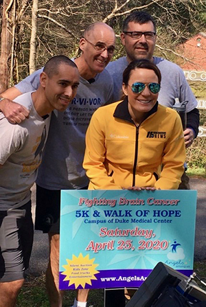 three men and one woman in front of a walk for brain cancer sign
