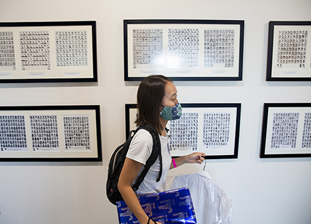 Maggie Min walks past photos of previous classes of medical students carrying her white coat
