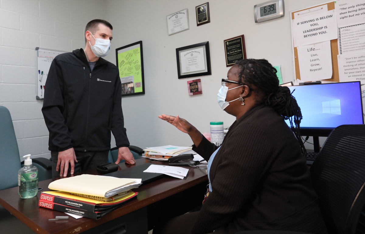 Colin Smith and Charita K. McCollers, talking over Charita's desk