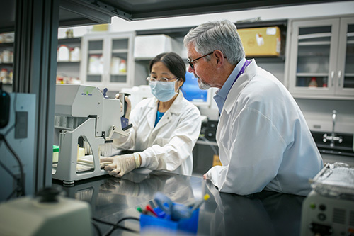 Kelso in his lab with a masked researcher looking at samples