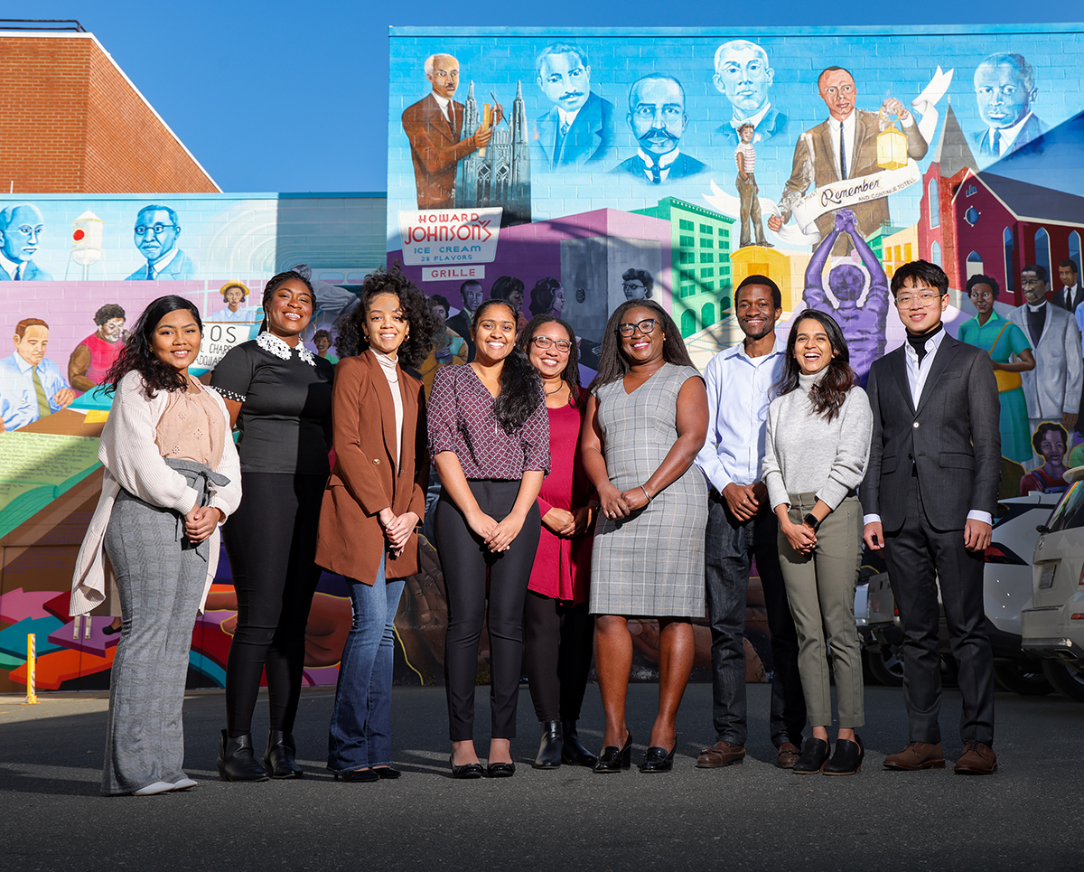 group photo of people standing infront of mural