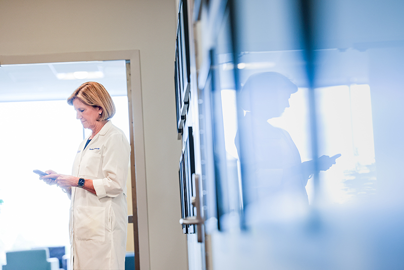 woman standing in hallways looking at phone