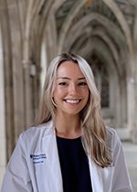 Student Victoria Lue wearing white coat standing under archway