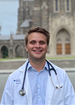 Student Michael Snider wearing whitecoat & stethoscope in front of Duke Chapel