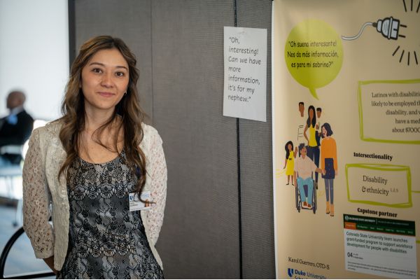 A dark haired young lady standing in front of a poster