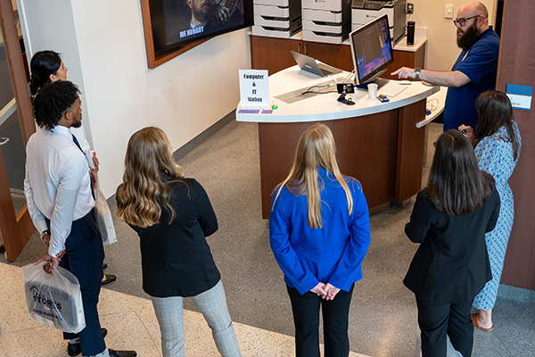 students standing around a desk listening to an IT specialist talk