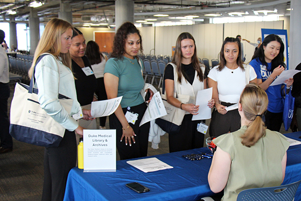 students standing around a fair booth listening