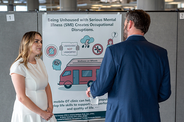 Dr. Bailliard talking with a Duke OTD student beside her poster