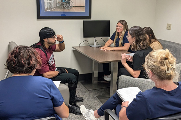 5 students and a client volunteer sitting around a table talking