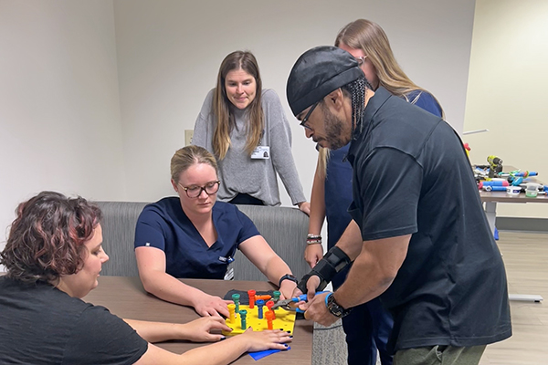 a client volunteer working with occupational therapists on a hand tool activity