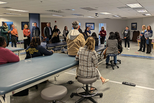 guests look on as a Duke DPT faculty member gives a tour of a rehab space