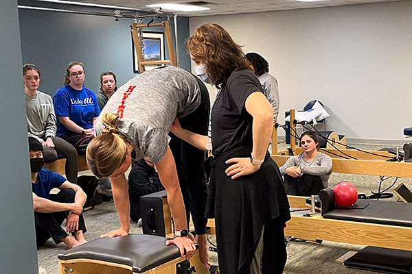 a physical therapist working with a woman while students look on