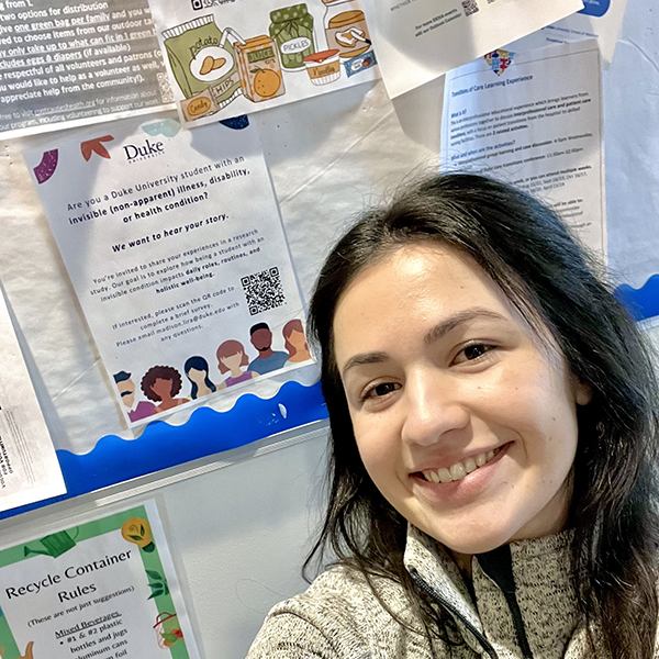 Maddie posing in front of a bulletin board and her research flier