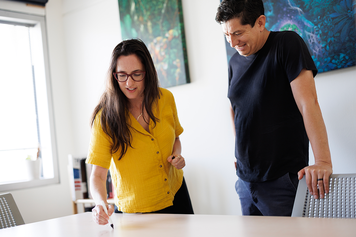 Naama Reicher, PhD, and Diego Bohórquez, PhD working on a whiteboard table in the lab