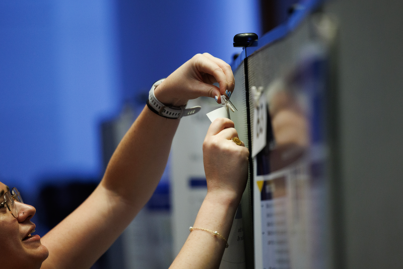 Katie Freedy, MS4, hangs her poster during the student poster presentation portion of the 56th Annual Duke School of Medicine Student Research Symposium