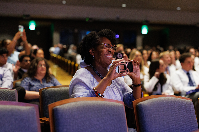 Proud parents watching their children from the audience at the white coat ceremony. 