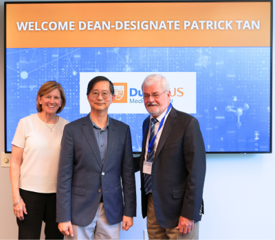 Image: Dean Mary Klotman, Duke-NUS Dean-designate Patrick Tan, and Edward Buckley, MD, pose in front of a screen that reads "Welcome Dean-designate Patrick Tan."