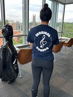 Student modeling the musical rounds t-shirt