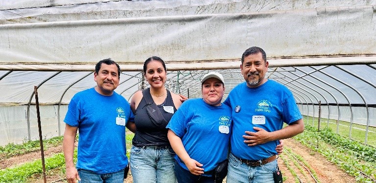 Elizabeth Rojo pictured with farmworkers in a greenhouse with crops.