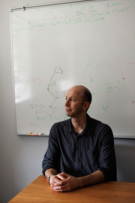 Herman Pontzer sitting in front of a whiteboard