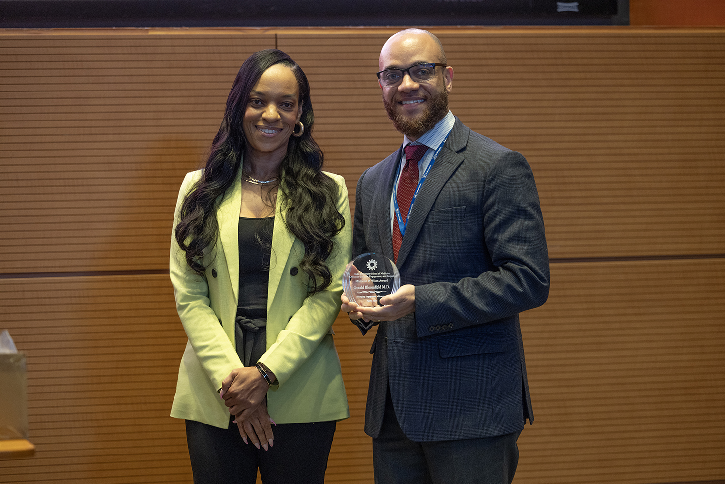 Two people smiling holding an award