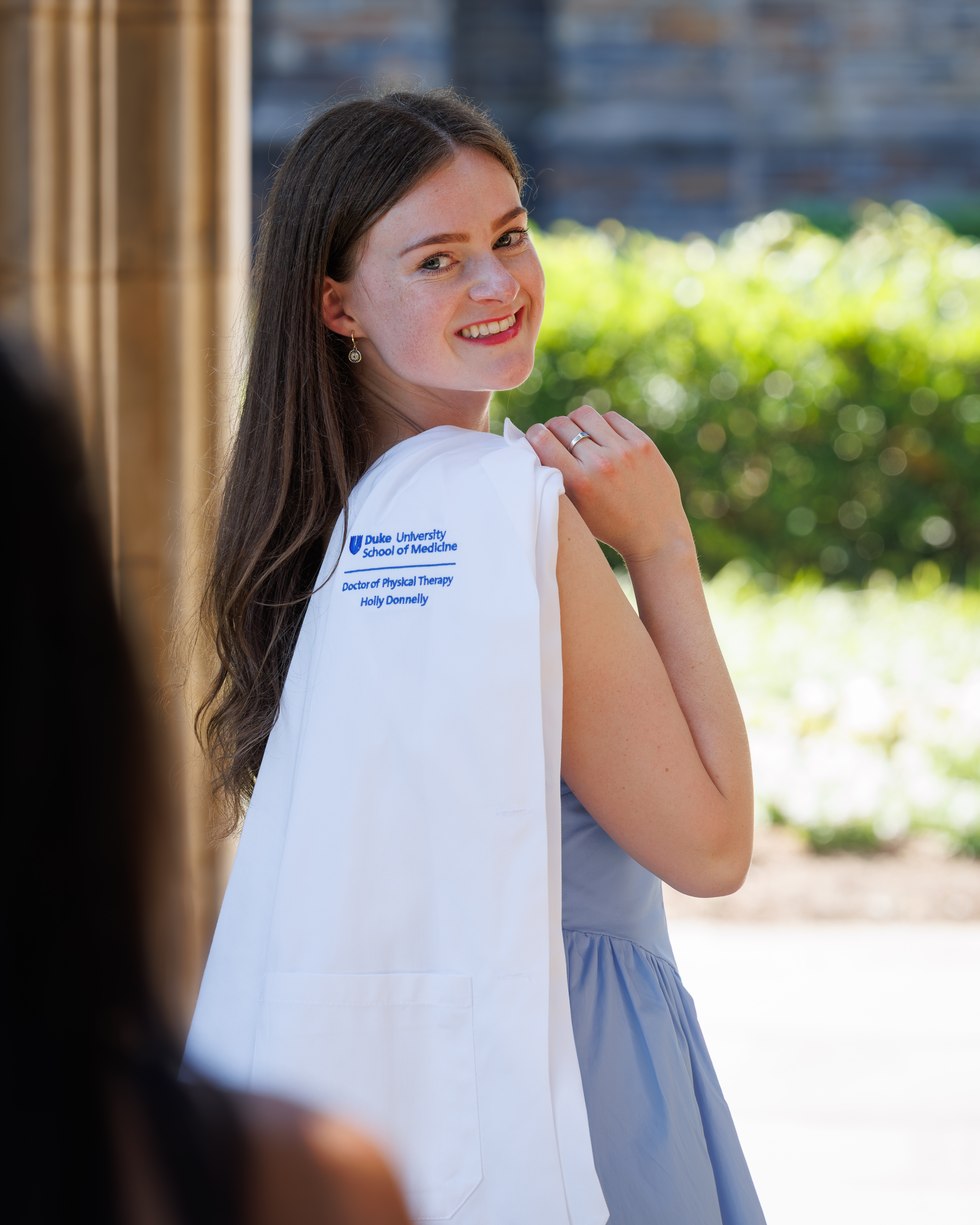 Smiling student looking over shoulder with white coat