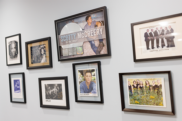 photos of those helped by voice care framed and mounted on a wall. 