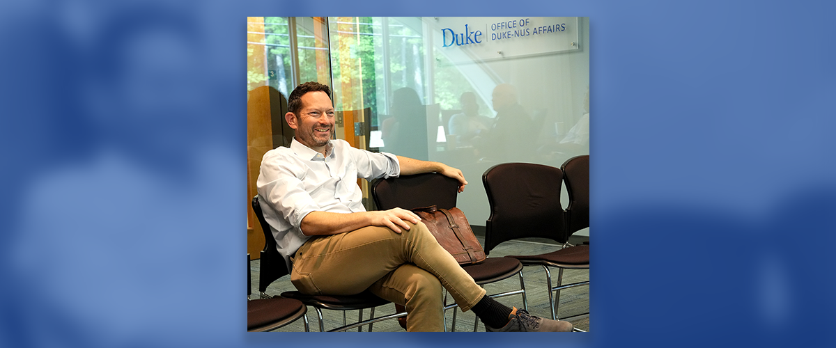 Image: Micah Luftig, Ph.D., seated in a meeting space at the Office of Duke-NUS Affairs.