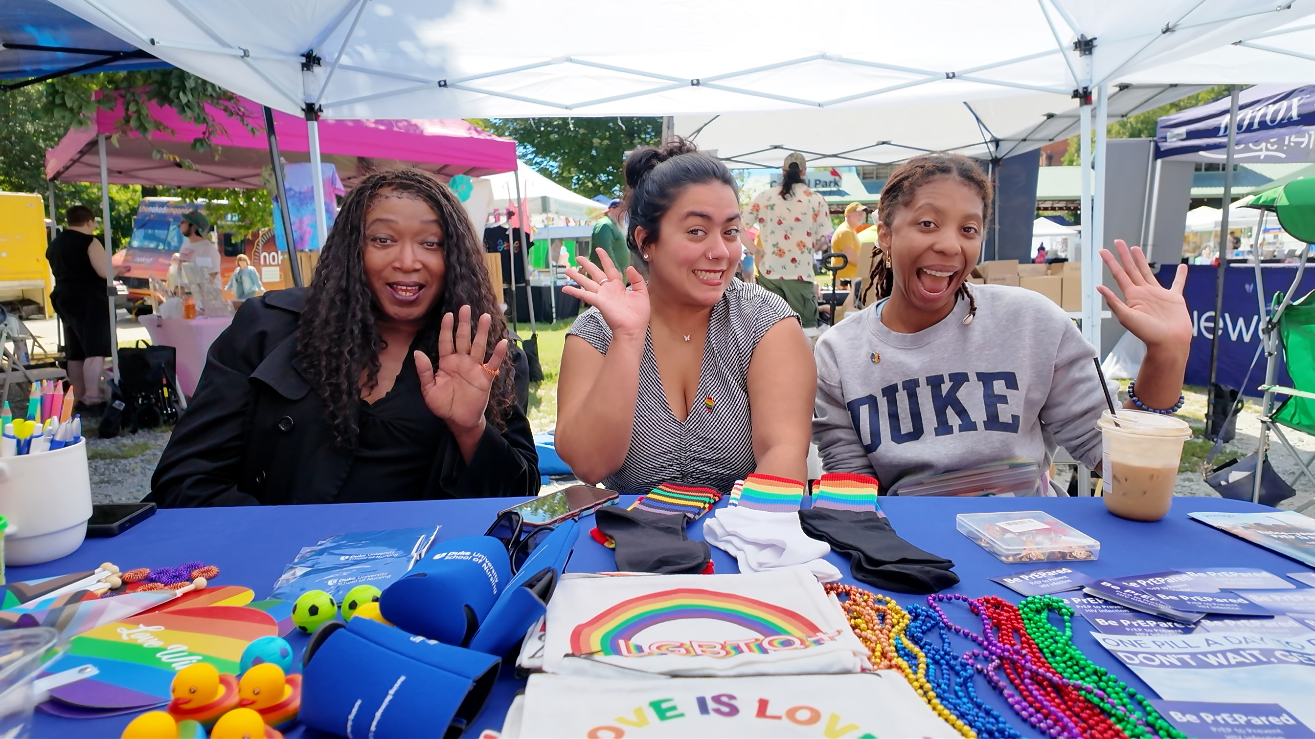 Three women smile and wave at Duke PrEP Clinic booth