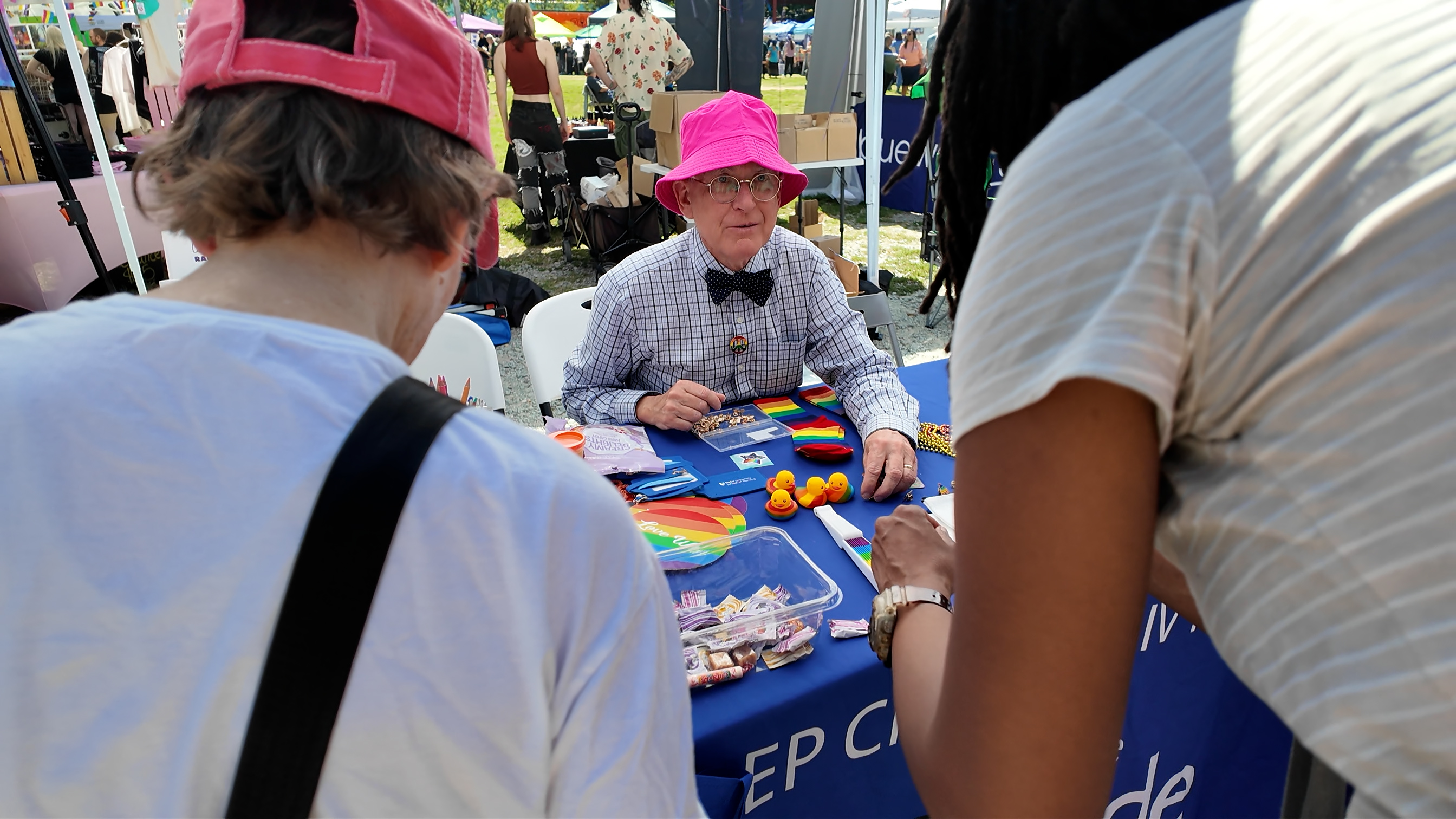 Man in pink hat hands out resources at Durham Pride