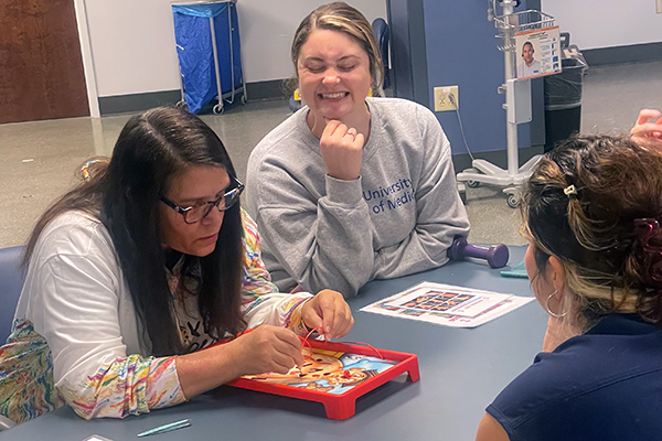 a woman playing the game Operation as an OT looks on