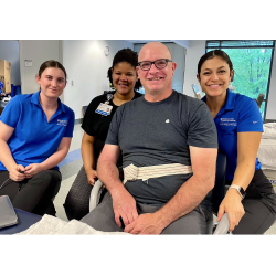 a man sitting with three clinicians/students