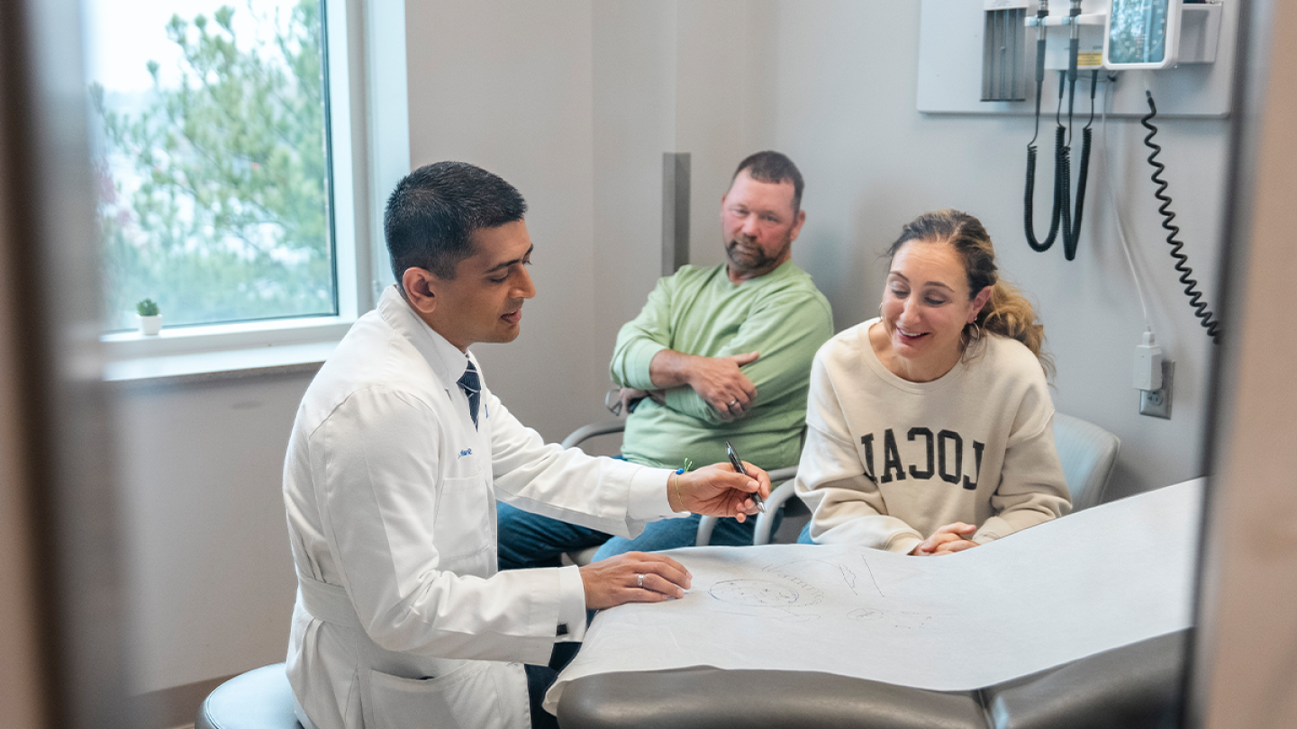 Physician consulting with patients in an exam room. 