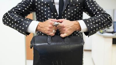 beringed physician's hands holding an old fashioned leather doctor's bag