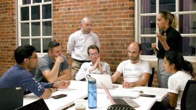 group of 7 people around a table with laptops