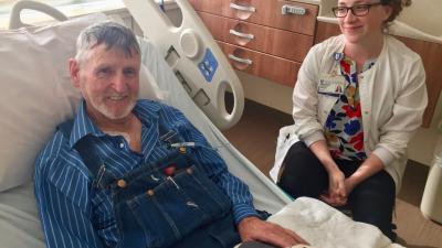 man in hospital bed with provider sitting next to him