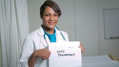 Dr. Kanecia Zimmerman holding a sign that say "Safe Treatment"