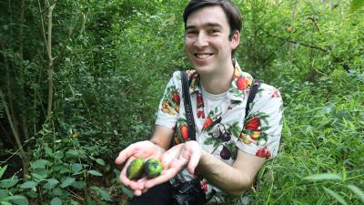 Jeff Letourneau in the woods holding 2 freshly picked paw paws