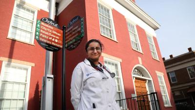 Rashmi Saincher, MBBS in her white coat standing outside brick building