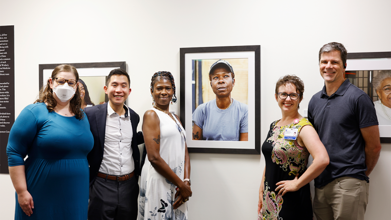 Butterfly Miles, center, poses near her portrait with the team during the opening of the Untold Stories Exhibition at the Duke University Medical School Library in Durham, 