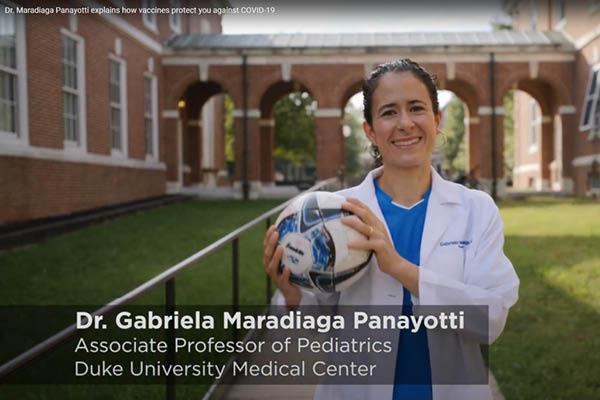 Dr. Maradiaga Panayotti in her white coat, outside holding a soccer ball
