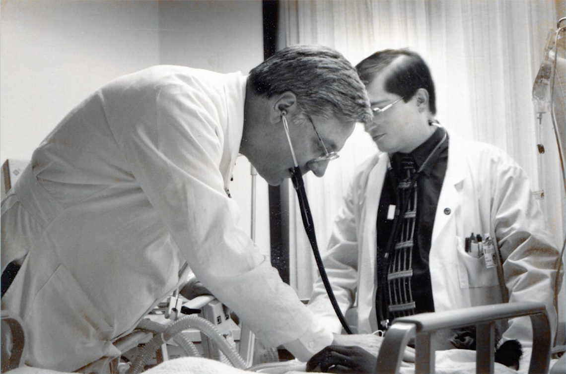 Dr. Fulkerson treating a patient in the hospital with a staff person standing by.
